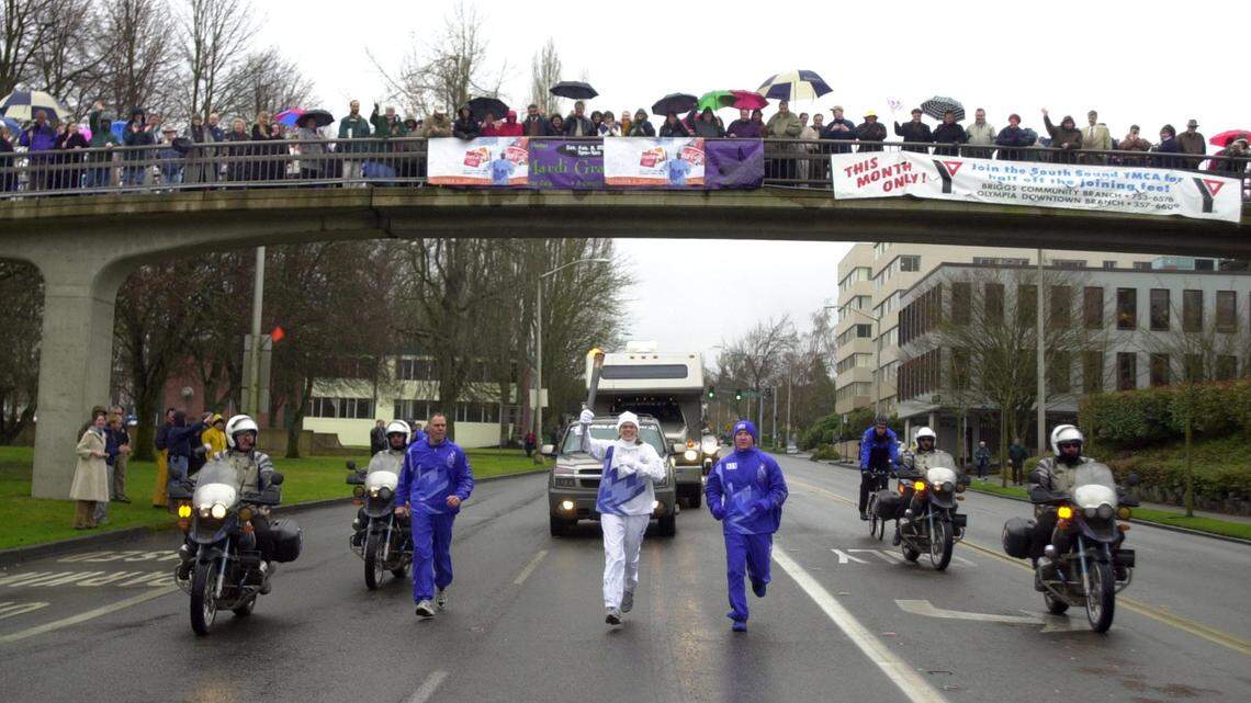 Spectators line the pedestrian bridge over Capital Way as Tara Sebagh of Clawson, Michigan, carries the Olympic torch in 2002. (Tony Overman/The Olympian)