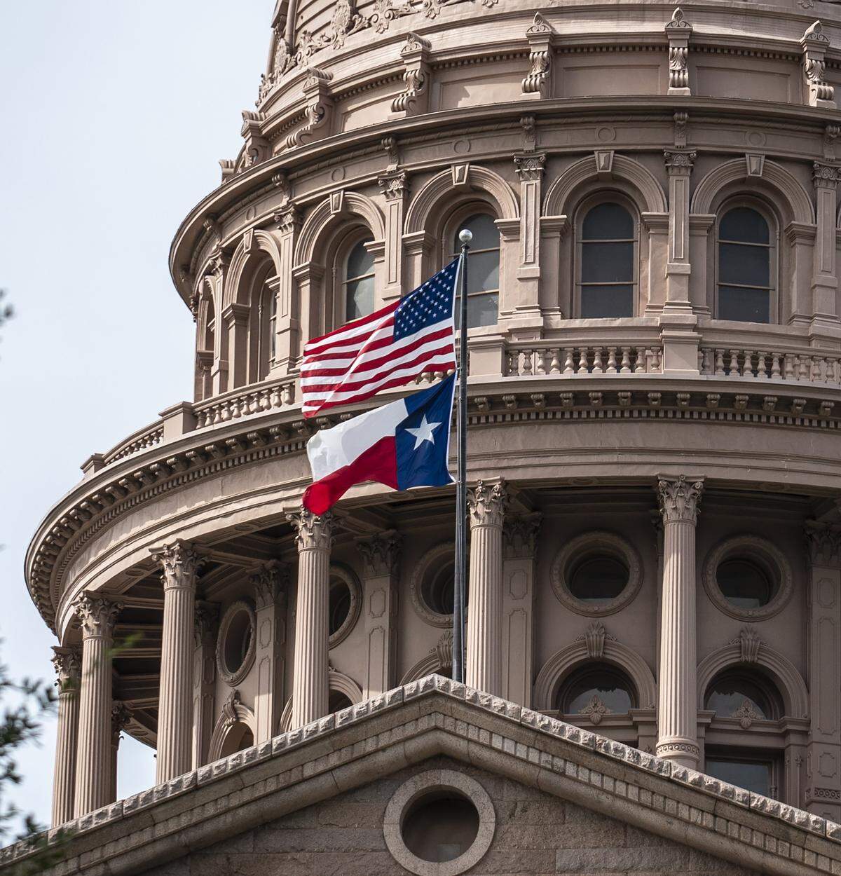 The U.S. and Texas state flags fly outside the state Capitol building on July 12, 2021, in Austin, Texas. (Sergio Flores/Getty Images/TNS)