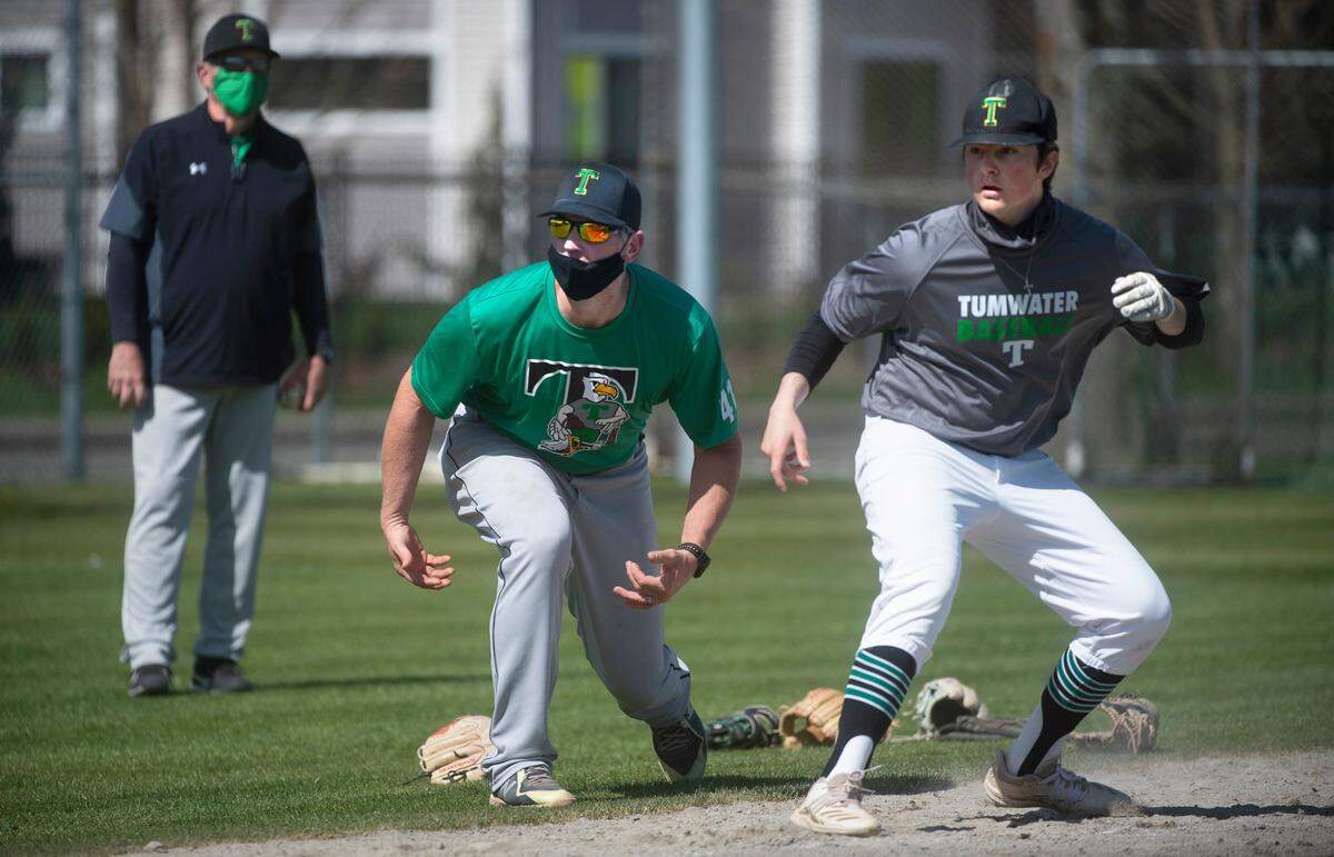 Tumwater baseball head coach Lyle Overbay runs drills alongside senior third baseman Conner Bourbon during T-Bird baseball practice at Tumwater High School on Tuesday, April 6, 2021.