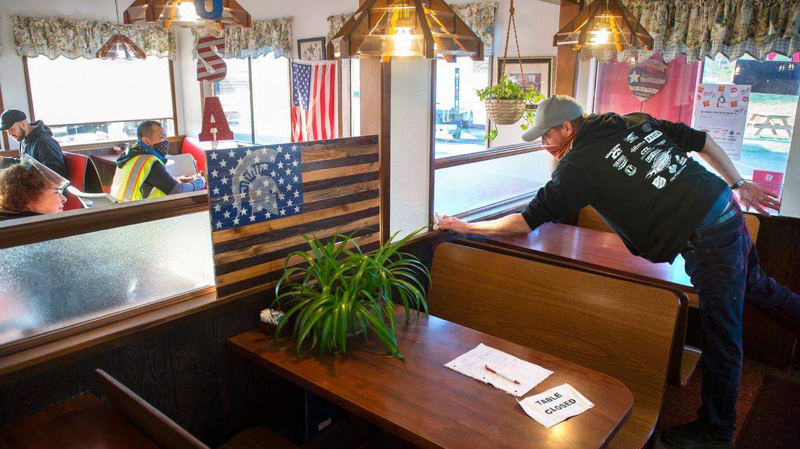 Farm Boy owner Brian Robbins sanitizes a table between diners at his restaurant near Maytown, Washington, on Friday, Dec. 4, 2020.