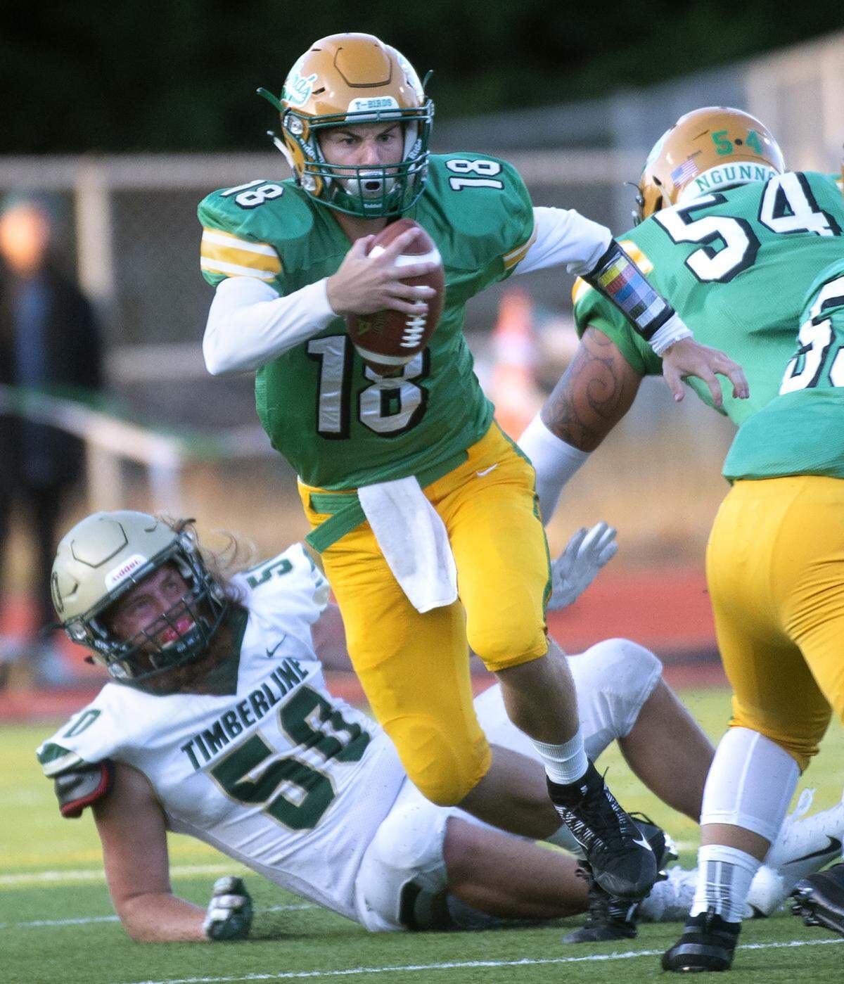 Tumwater quarterback Cody Whalen breaks loose in front of Timberline defender Blake Doss during Friday night’s season-opening football game at Tumwater District Stadium on Sept. 6, 2019.