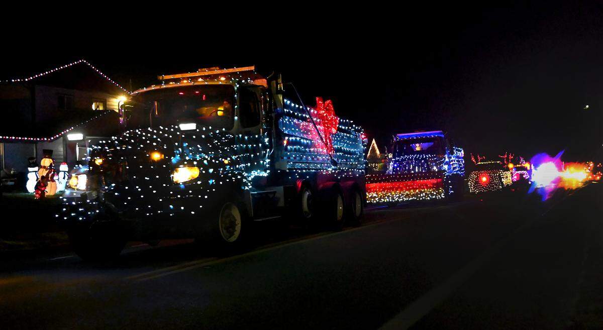 A convoy of City of Olympia vehicles decorated with holiday lights makes it way up 22nd Avenue Southeast during a past Holiday Light Parade.