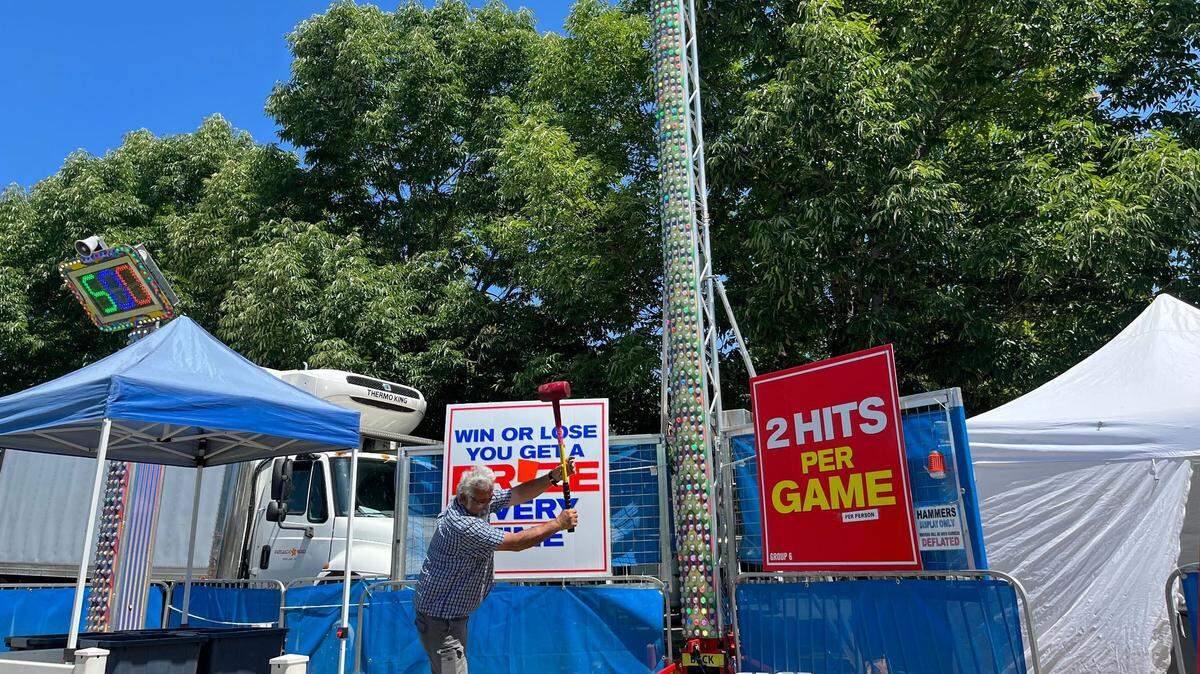 A carnival worker tests the strongman machine that will be a part of Capital Lakefair. Everyone who plays wins a prize.