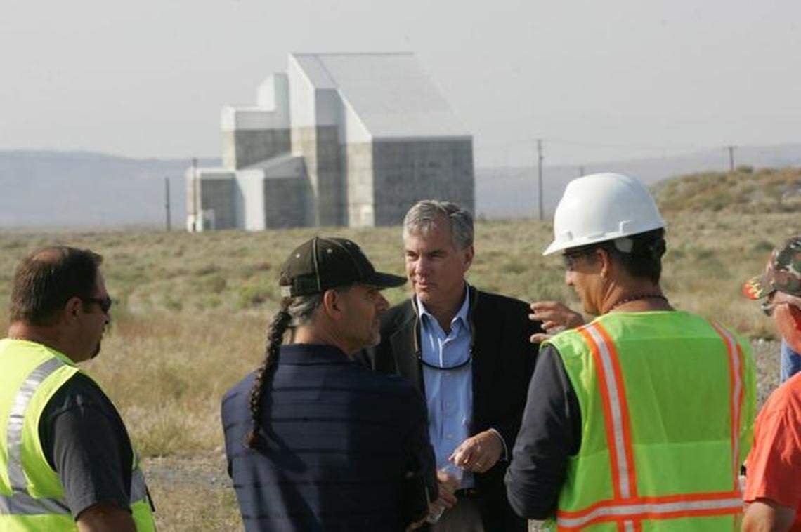 Hanford’s cocooned F Reactor stands behind officials touring the area around the reactor.