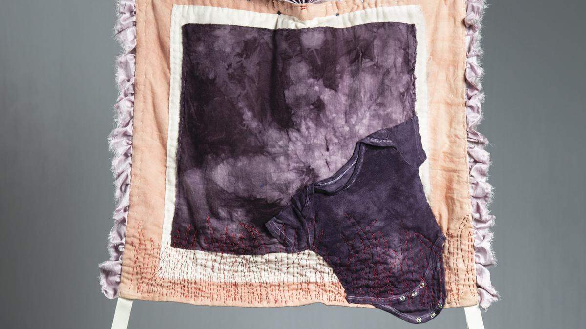 Faith Hagenhofer’s “Held Dear,” the piece the city commissioned for the Arts Walk cover, incorporates a baby’s onesie set against a dappled cloudy sky, with the composition framed as if within an architectural niche.
