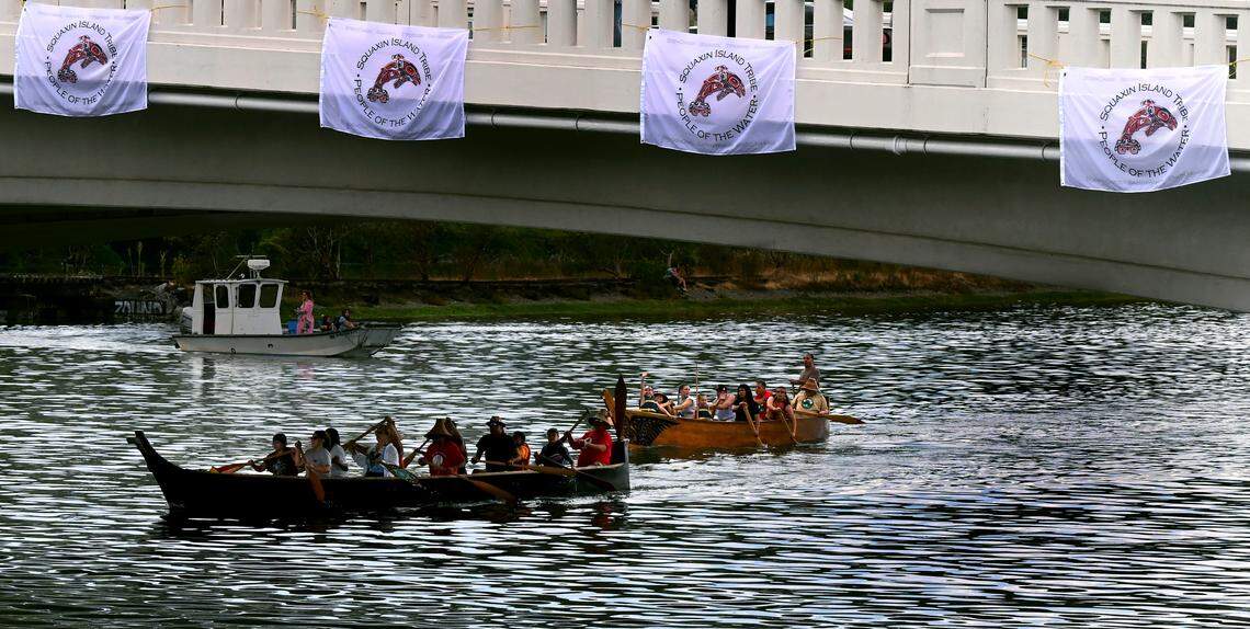 Tribal canoes pass under four Squaxin Island banners affixed to the Fourth Avenue bridge as part of the Healing of the Waters ceremony near the conclusion of the Festival of the st̓əč̓as celebration held in Heritage Park and along the banks of Capitol Lake in Olympia on Aug. 17, 2024. The festival, hosted by the Squaxin Island Tribe and the Deschutes Estuary Restoration Team, honored the landscape and the original inhabitants of what was once a Deschutes estuary and Budd Inlet, and celebrated the plan to remove the Fifth Avenue dam to allow Capitol Lake to revent to the estuary.