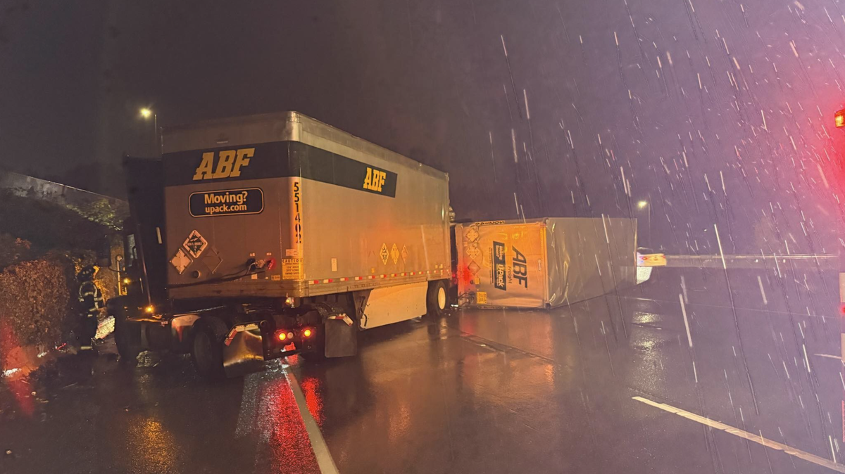 A Tumwater firefighter firefighter weathers the rain as they look into one of two semi-trucks that collided on Interstate 5 by milepost 104 on Tuesday, Oct. 28, 2025.