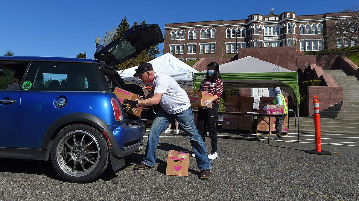 Thurston County Food Bank volunteers load bags and boxes of food into waiting vehicles at a drive-thru distribution point set up Thursday at the steps of the Grand Staircase on the Saint Martin’s University campus in Lacey. Jones said the next distribution day at the university is scheduled for April 23.