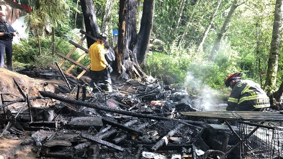 Olympia firefighters sift through debris after extinguishing a fire inside “the Jungle” homeless encampment off Martin Way.