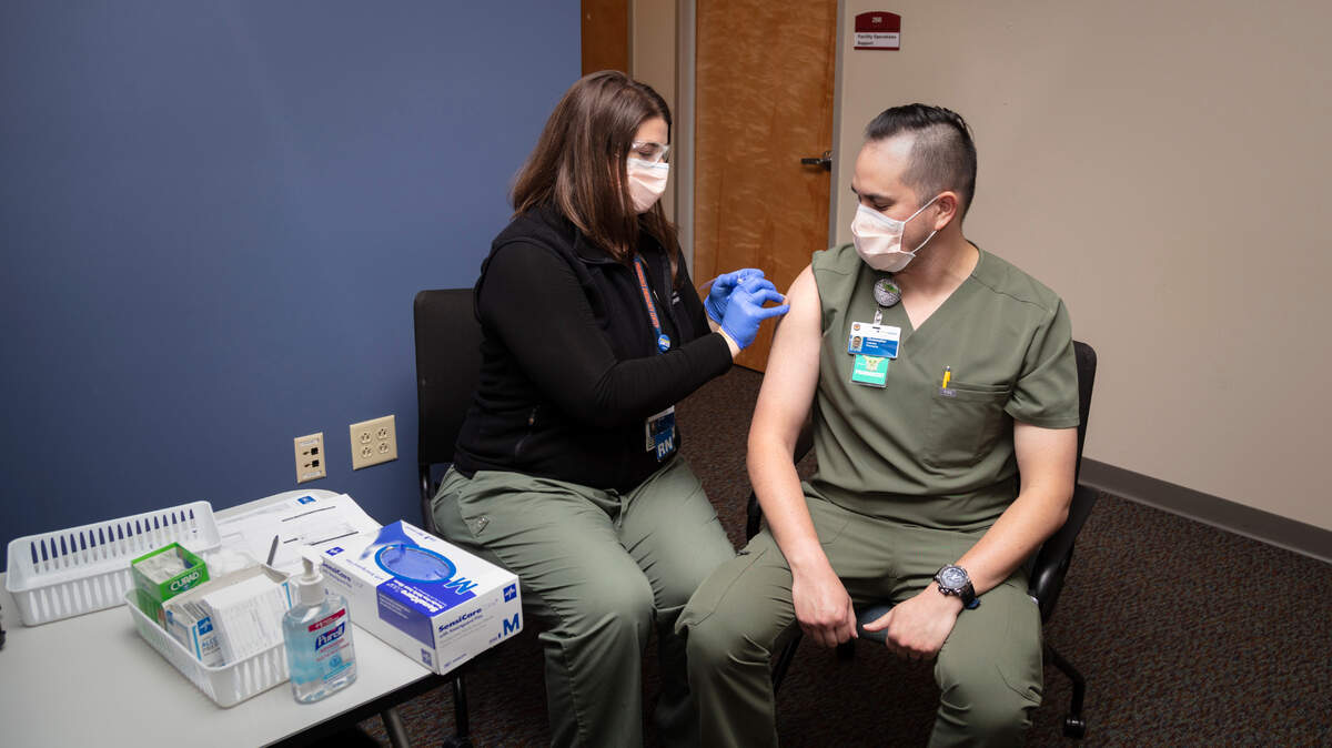 Ashlynn Strode, an ER nurse at Providence St. Peter Hospital in Olympia, administers the COVID-19 vaccine to Providence Centralia Hospital ER pharmacist Christopher Andrews on Friday. They were among the first to receive the vaccine in Thurston County.