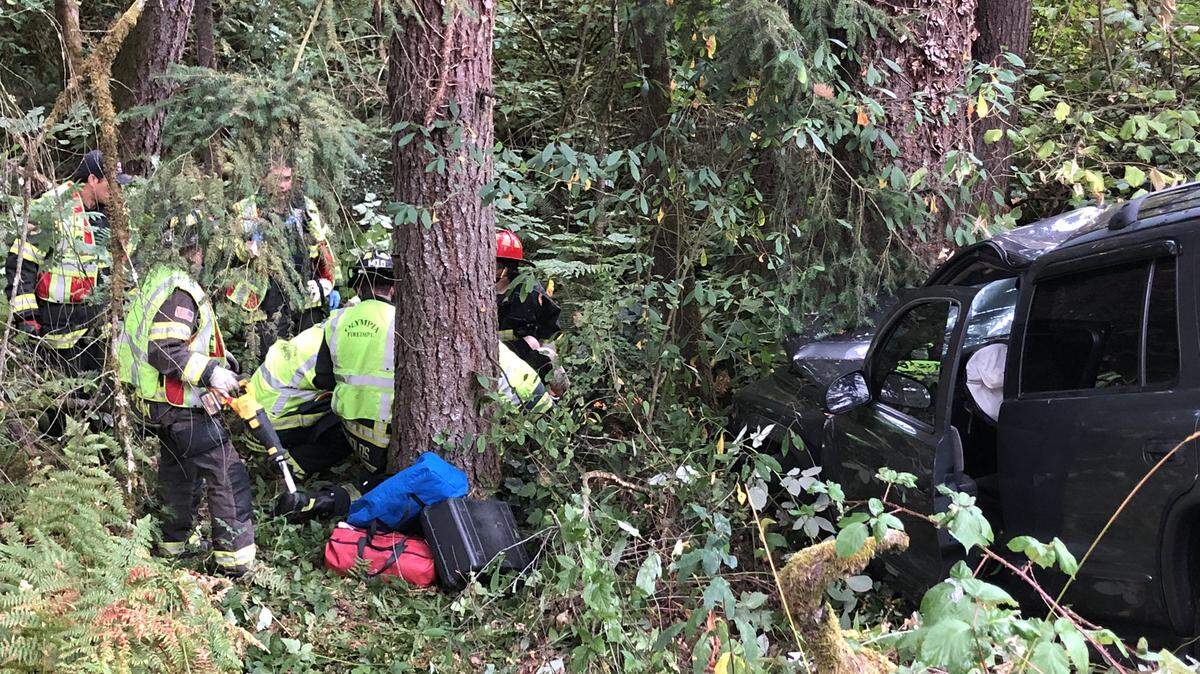 Aid workers respond to a car that crashed into a tree at the intersection of Cooper Point Road and Conger Ave
