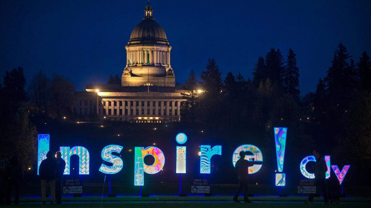 With the state Capitol in looming in the background the Inspire! Oly art installation shines under black lights at Heritage Park in downtown Olympia, Washington, on Saturday, March 26, 2022. Voters approved Proposition 1 - aka the Cultural Awareness Initiative - allocating 1/10th of 1% of a statewide sales tax to support and provide access to the arts.