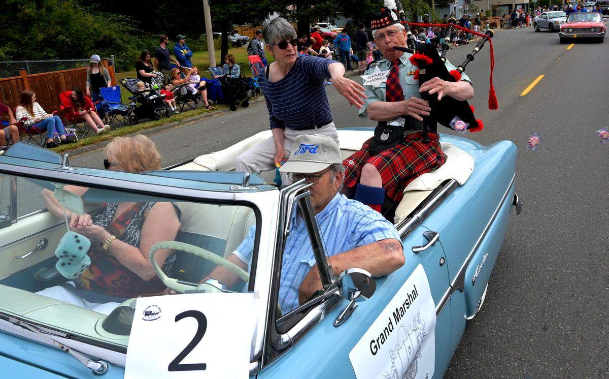 Resplendent in the traditional tartan uniform he wears when playing with the Olympia Highlanders Bagpipe & Drum Corps, renowned Tenino stone carver Keith Phillips fills Sussex Avenue with the sounds of the bagpipes as Grand Marshal for the annual Oregon Trail Days Parade on Saturday, July 23, 2022. Seated with friend Anne Sweringen, who tossed candy to eager kids along the route, the couple were chauffeured in style by Joe Kanke and Joanne Gripp in his vintage 1954 Ford Crestline convertible.
