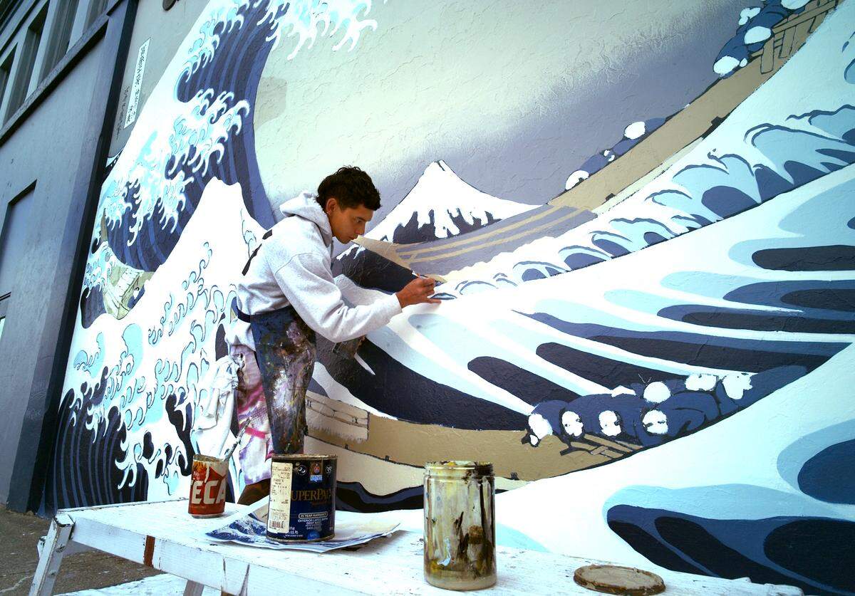 Painstakingly finishing every detail big and small, local artist Austin Davis has worked restoring the landmark “Great Wave” mural that has adorned the west-side wall of the Childhood’s End Gallery in downtown Olympia since 1977. The mural’s creator, well-known regional artist Joe Tougas, has been observing the project and even added his expertise by handling some of the fine handwork detailing.