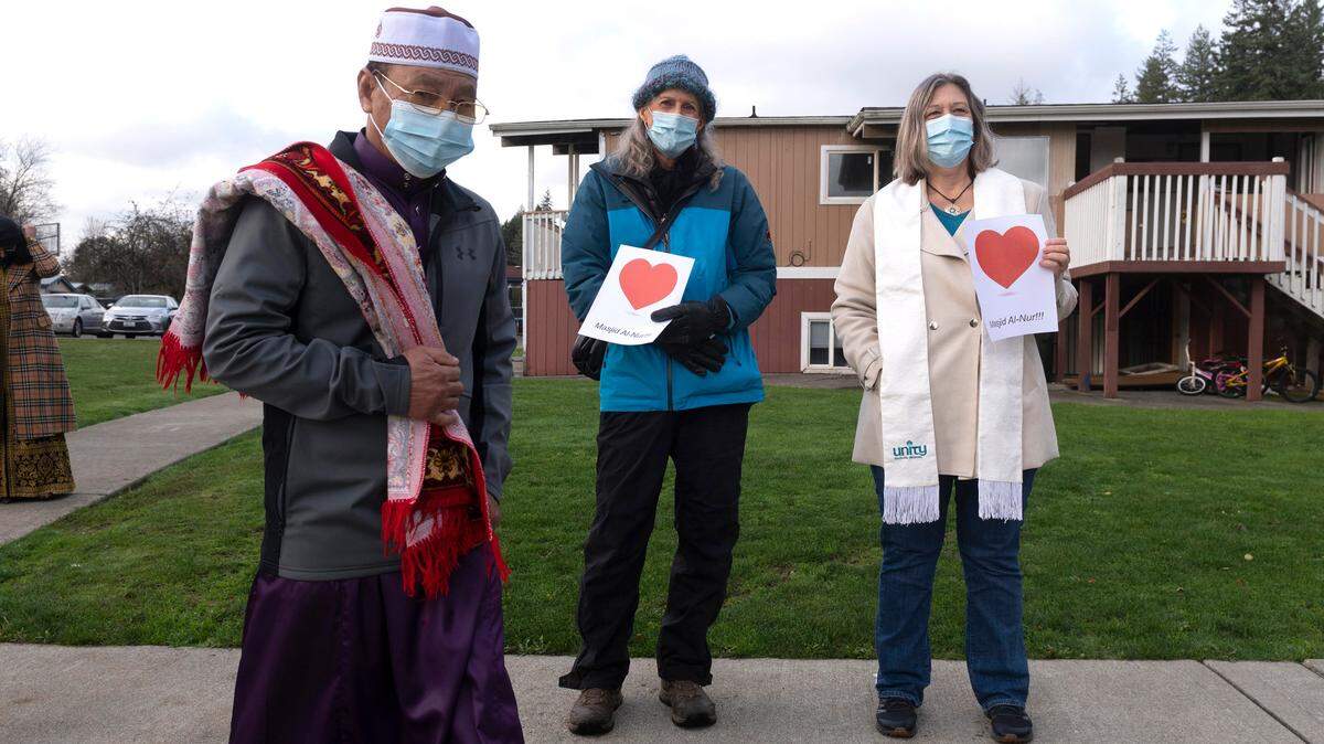 Jamie Rainwood (center) of Community for Interfaith Celebration, and Rev. Terry Murray of Unity of Olympia, stand in support of the Islamic Center of Olympia in Olympia, Washington, on Friday, Dec. 3, 2021.