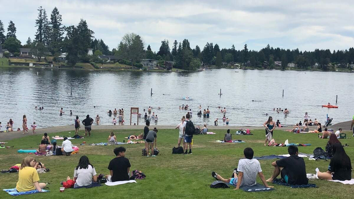 Families splash around at Long Lake Park in Lacey in June. Swimming has been temporarily restricted to the shallow water because of poor water visibility.