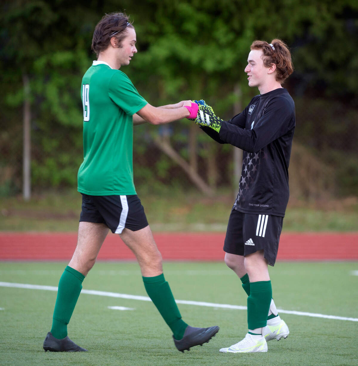 Tumwater defender Jack Armour (left) and goalkeeper AJ Heichlebech celebrate a T-Bird goal during a soccer match against the Rochester Warriors at Tumwater District Stadium in Tumwater, Washington, on Friday, April 16, 2021.