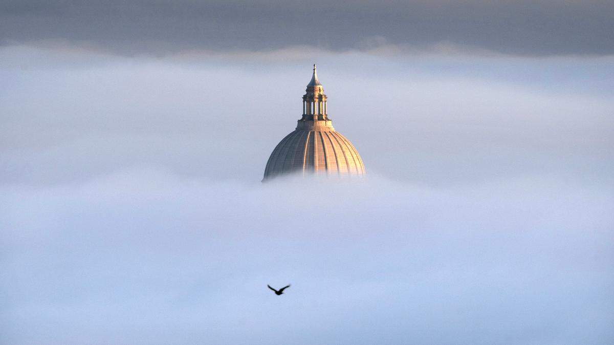 The Washington State Capitol pops out of the thick fog on a freezing morning as seen from Overlook Park in Tumwater, Wash.