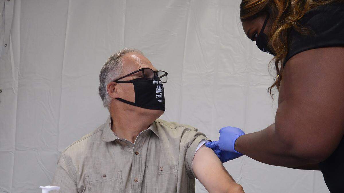 Registered Nurse Cenetra Pickens finishes up giving Gov. Jay Inslee his flu vaccination on the Capitol Campus in Olympia Thursday morning. Inslee joined over 200 state employees who received their flu shots at the one-day, drive-thru clinic in the East Plaza parking garage. Hosted by Kaiser Permanente and SEIU Healthcare 1199NW, the clinic was conducted to encourage Washingtonians to get flu shots, according to a news release.