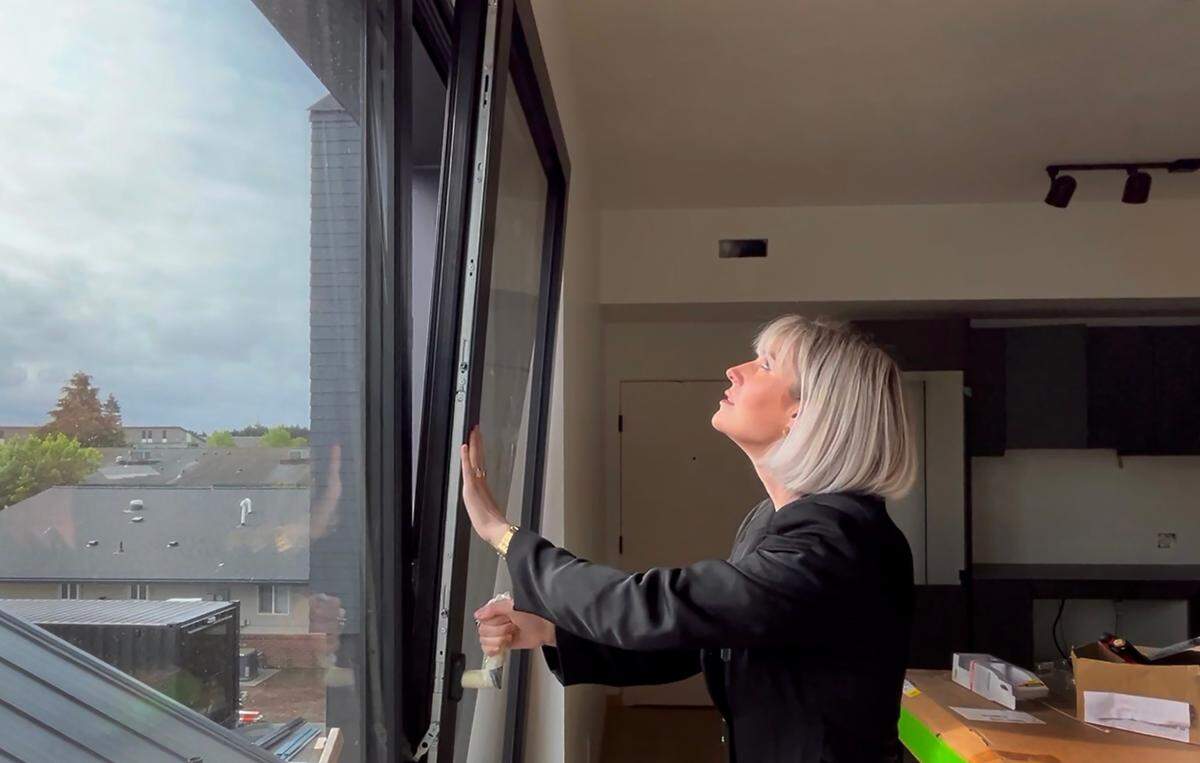 Artisan’s Group co-owner Tessa Bradley demonstrates a window in an apartment that not only opens left to right but also from top to bottom.