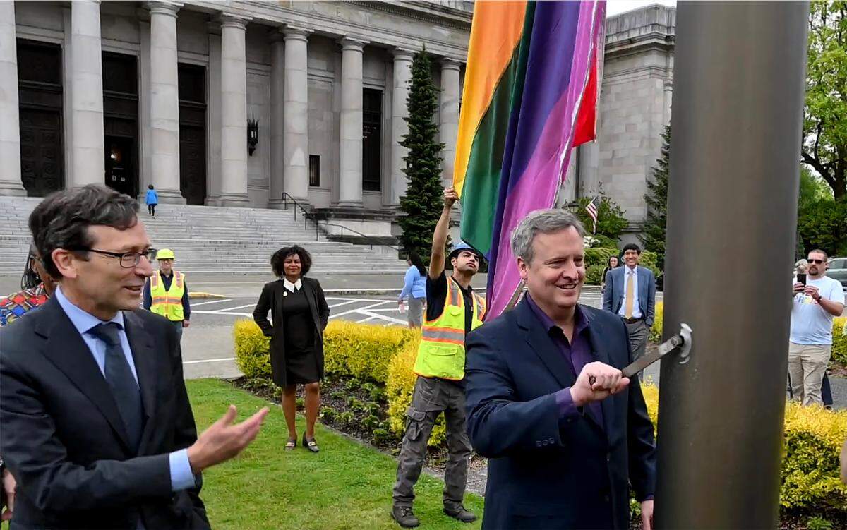 With Gov. Bob Ferguson looking on, Commissioner of Public Lands Dave Upthegrove takes his turn to raise the Pride flag Wednesday, June 4, at the flag circle on the Capitol Campus.