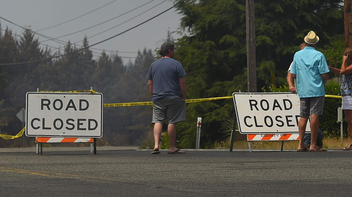 Residents and passersby watch fire crews on East McEwan Prairie Road near Shelton on July 5.