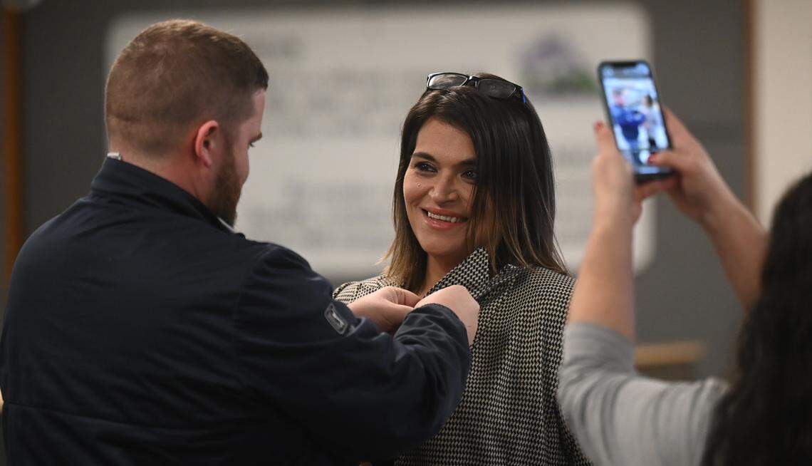 Newly elected Thurston County Commissioner Rachel Grant receives some assistance in pinning on a county pin by her husband Jeff before the Dec 17, 2024 swearing in ceremony at the Atrium building in Olympia which houses county services.