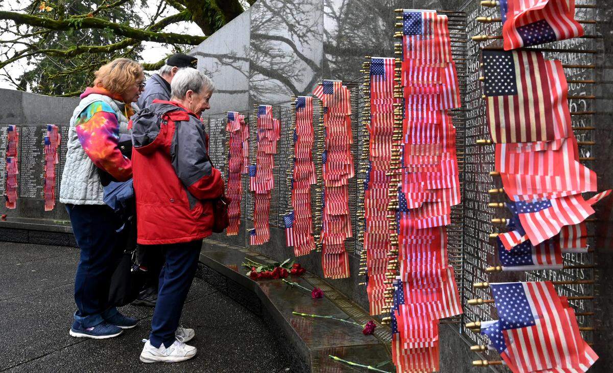 Two woman pay tribute to Vietnam war veterans at the Vietnam Memorial Wall, just north of Sid Snyder Avenue Southwest on the state Capitol Campus in Olympia. The Sacajawea Chapter of the Daughters of the American Revolution honored those who served in the war with a ceremony that included the reading of names on the wall, and a pinning ceremony for the spouses and other family members of deceased Vietnam veterans.