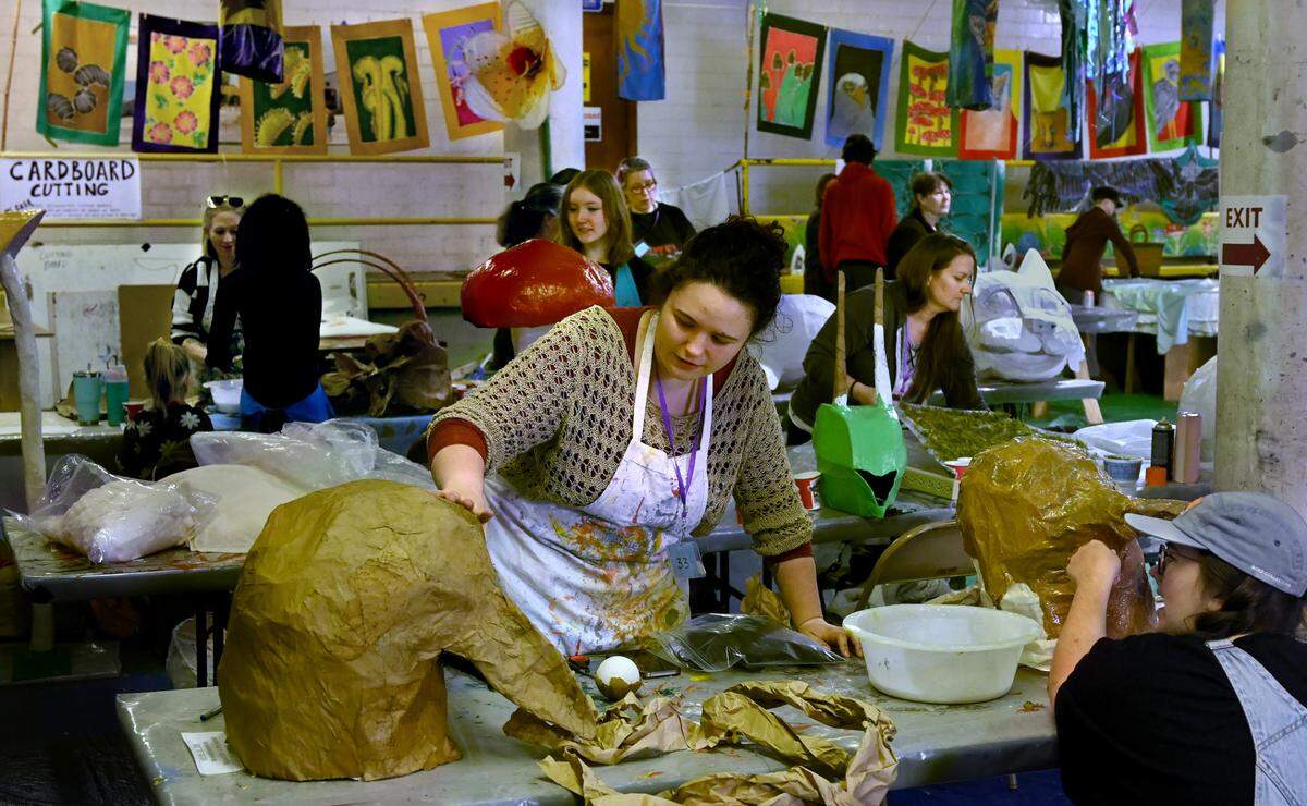Working at a bustling Procession Art Studio at the Armory Creative Campus, Olivia Richards and Ella Sharrett craft lightweight heads for raven and loon bird puppets that will take flight in the annual Procession of the Species on Saturday in downtown Olympia. New for 2025, the Procession has added an “estuary” section to its traditional four elements of earth, air, fire and water. People have been working for weeks at the Armory to create their flora and fauna for this year’s event.