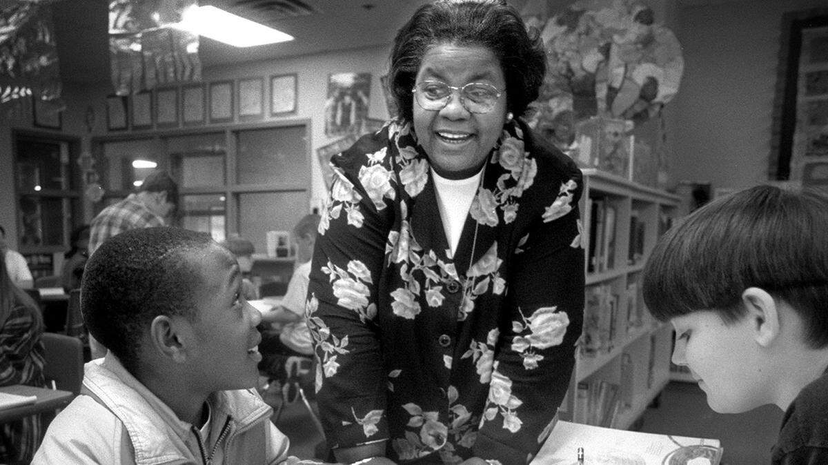 In 1997, in the library at Seven Oaks Elementary School in Lacey, 20-year North Thurston school board veteran Thelma Jackson talks with sixth graders Amiah Oates (age 10), left, and Josh Aken.