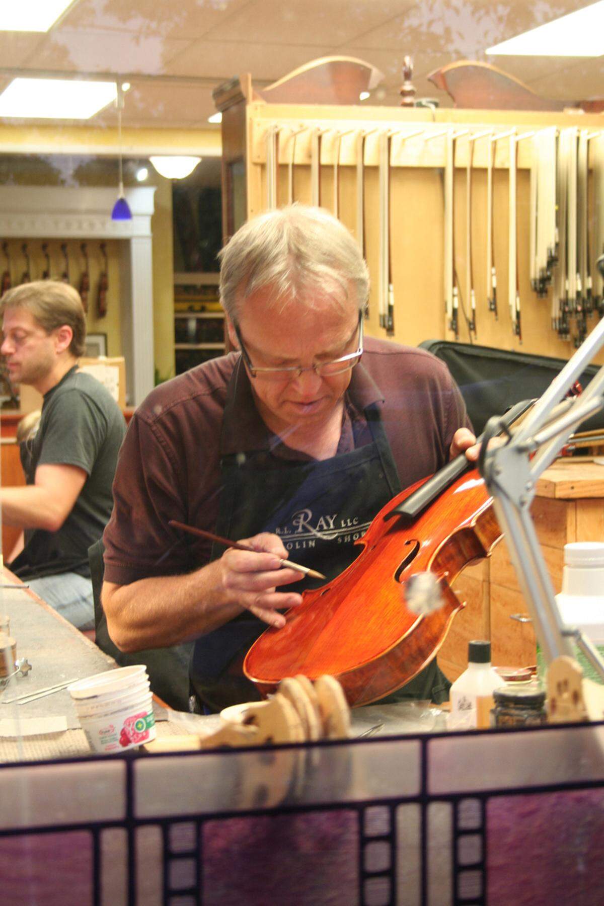 Olympia’s Robert Ray fixes a viola. Jon Hanson, the current owner of RL Ray Violin Shop, is in the background on the left.