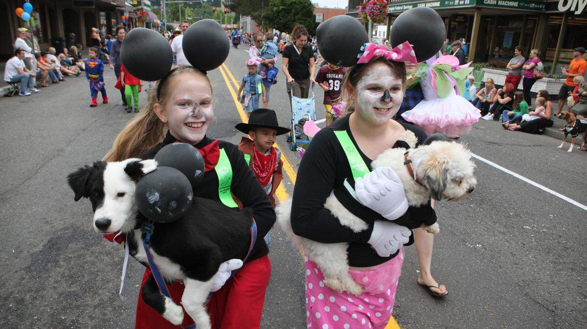 Sydney Wagner (left), and Meghan Callender carry their dogs Teddy and Mups up Fifth Avenue during the 2012 Pet Parade in downtown Olympia.