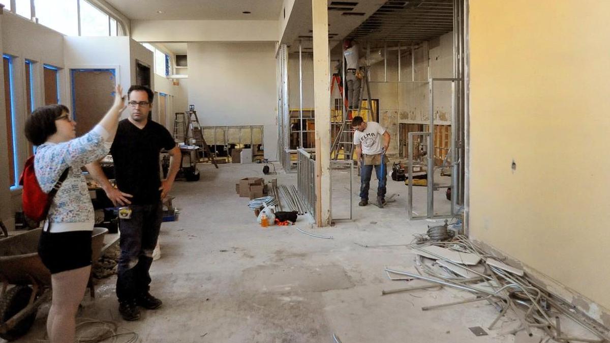 Little General Food Shop employee Samantha Margerum discusses interior work with Adam Broomfield, the general contractor, on June 7th as the downtown Olympia store prepares to move into the former location of the Acqua Via restaurant at Fifth Ave. and Capitol Way. In the background, electricians Brennan Baker, Chris Whaley and Dan Scherer (not pictured) of Reliable Electric rewire the site.