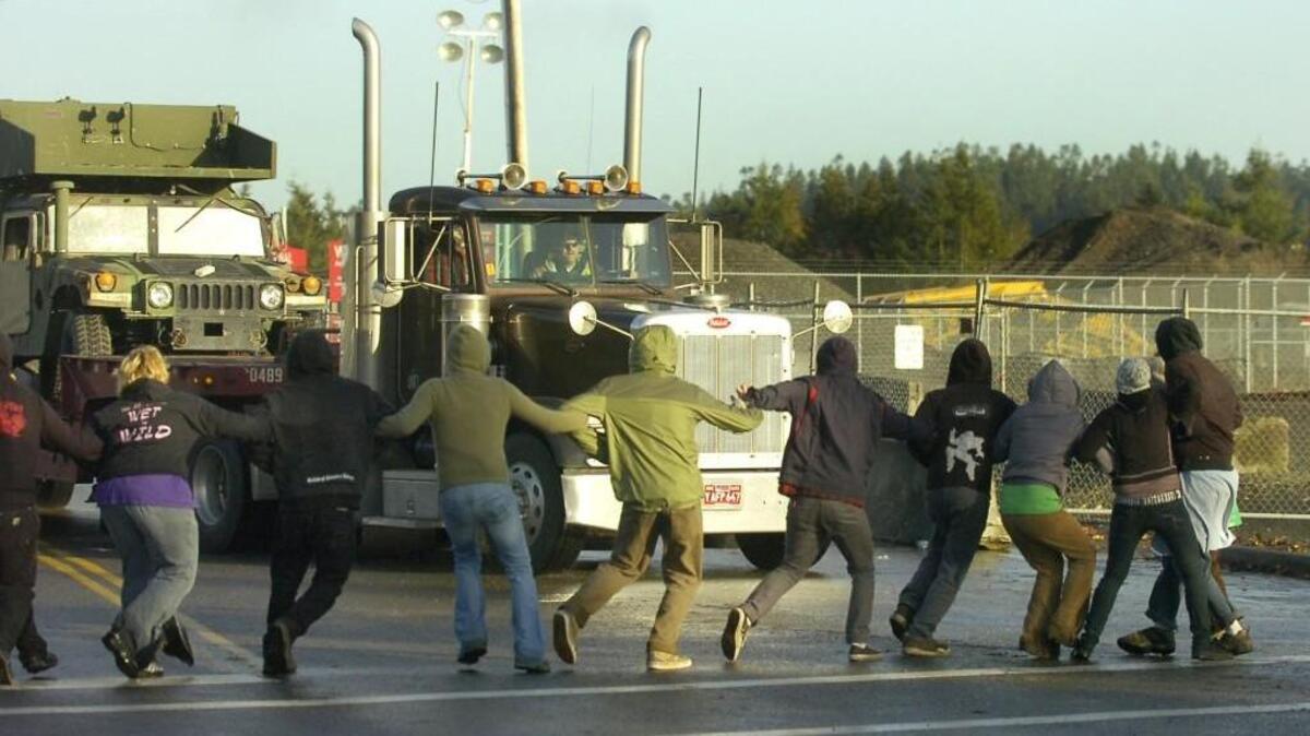 A military convoy truck driver makes a dash toward a rushing line of protesters Nov. 14, 2007, at the marine terminal entrance to the Port of Olympia. Most shipments were disrupted by a blockade.