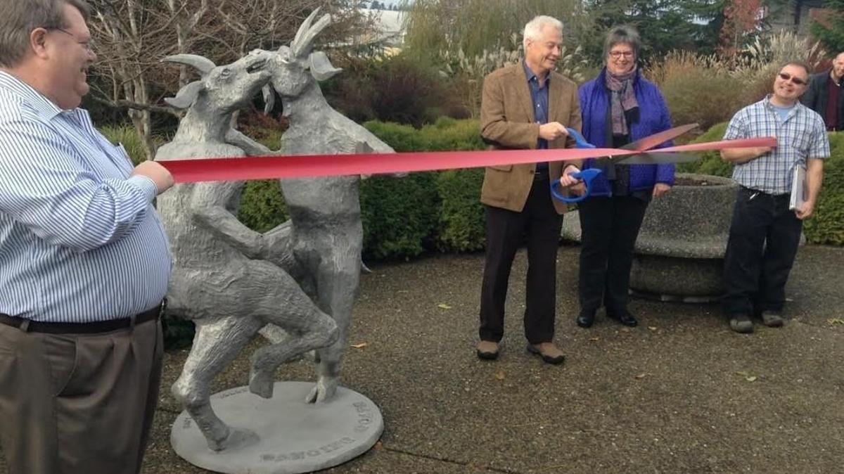 David Wasson, left, chief operating officer for Batdorf & Bronson, holds an end of a ribbon Tuesday as Batdorf co-owner Larry Challain gets ready to cut it in Olympia to celebrate the business’ expansion of solar energy producing capabilities. Standing next to Chillain is co-owner Cherie Challain.
