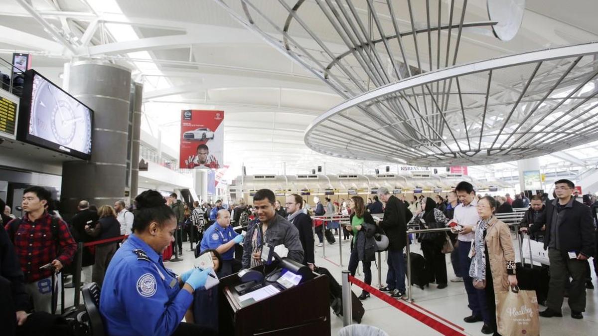 A TSA officer, left, checks a passenger's ticket, boarding pass and passport as part of security screening at John F. Kennedy International Airport in New York. Washington state was granted an extension to get into compliance with the REAL ID Act.