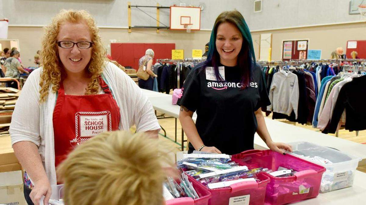 Tami Collins, left, a homeless liaison for the Tumwater School District, and volunteer Stephanie Maldonato hand out toothbrushes and toothpaste at the Little Red Schoolhouse Project's free school supply distribution at Komachin Middle School in Lacey 2016.