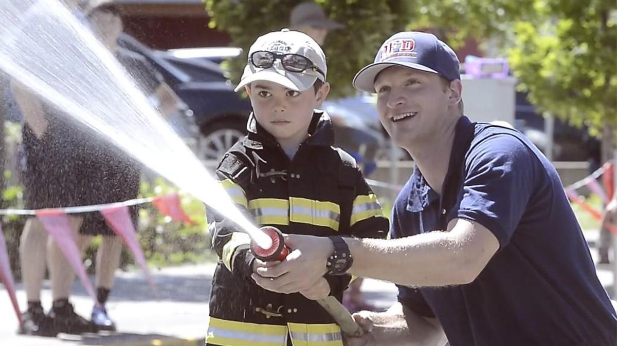 Olympia firefighter Devin Ferguson helps a young firefighter-to-be learn to spray a fire hose during the 2017 Fire Rescue Spectacular event at the Hands On Children's Museum in Olympia.