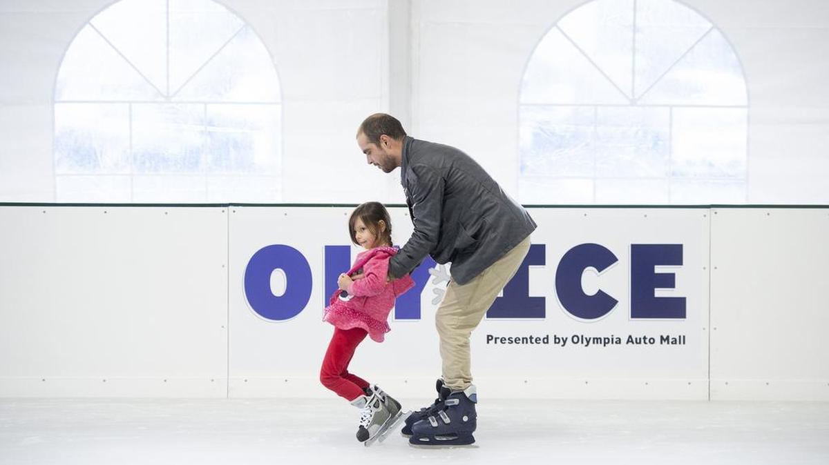 Michael Looney of west Olympia helps his daughter, Cara Looney, 5, as they hit the ice on opening day at the "Oly on Ice" seasonal skating rink at the new Isthmus Park in downtown Olympia.