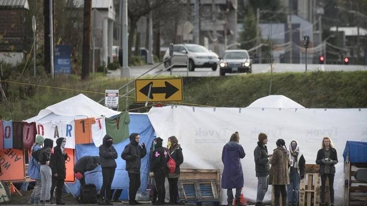 Protesters stand Tuesday outside a campsite that blocks railroad tracks in downtown Olympia. The protesters say they are against shipments of material used in fracking entering the country at the Port of Olympia.