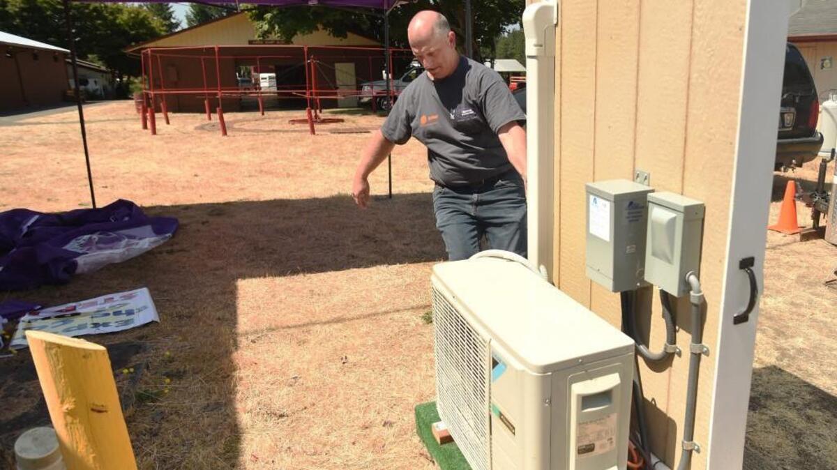 Chehalis Sheet Metal Heating & Cooling project manager Mark Skinner wheels a portable air conditioner into position at a cooling station near the information booth at the Thurston County Fairgrounds. The fair opens Wednesday.