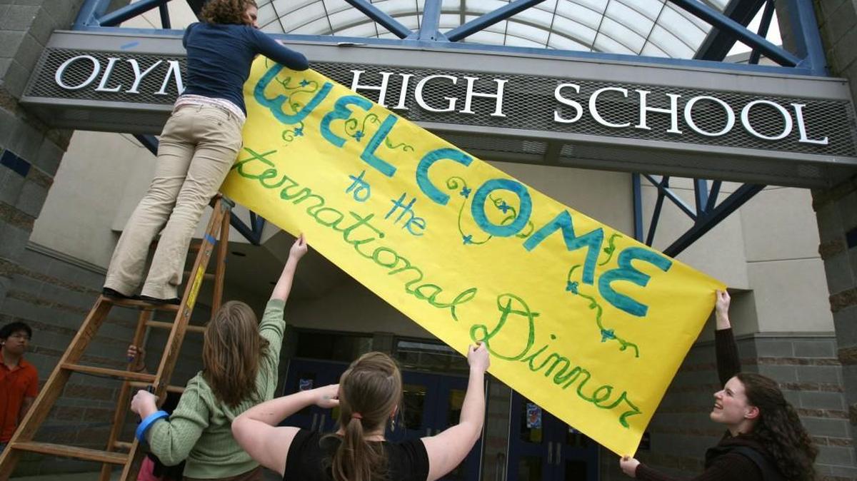 Rotary Interact Club member Brynn Sebring (upper left) gets help from National Honor Society members (from left) Ayla Mullen, Katie Anthony and Maggie Counihand hang a welcome sign for the fourth-annual International Dinner at Olympia High School on Friday, April 24, 2008. (Tony Overman/The Olympian)