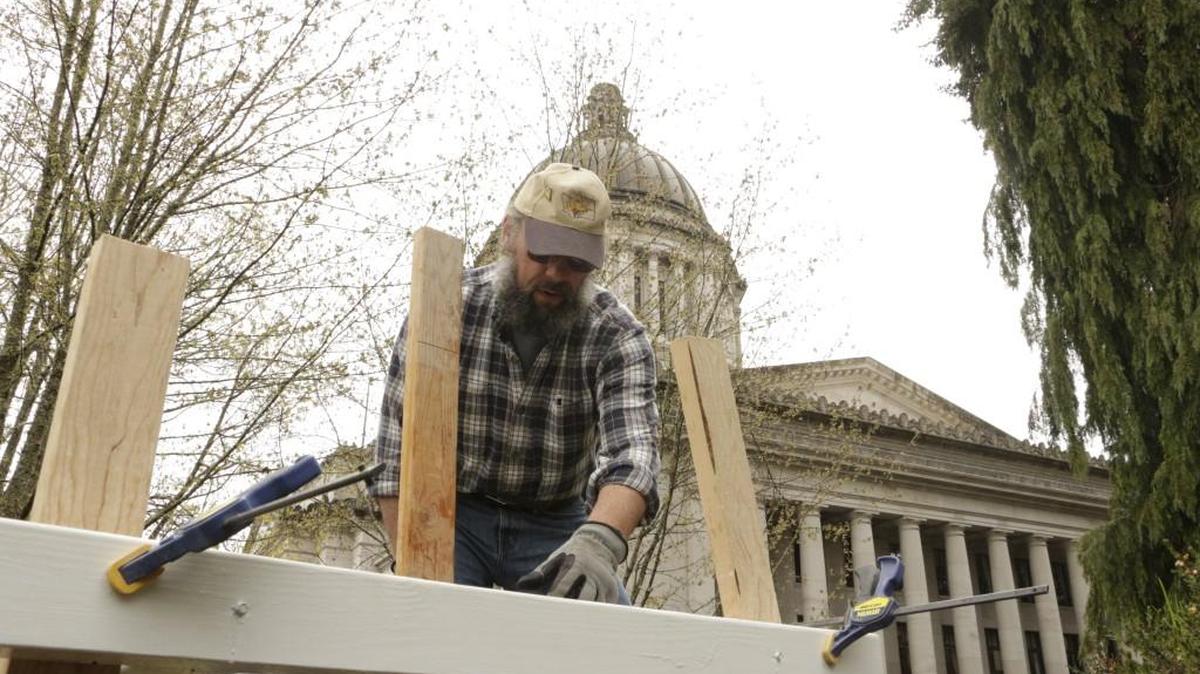 Olympia Beekeepers Association member Mark Emrich installs a base for hive boxes last week on the front lawn of the Governor’s Mansion..
