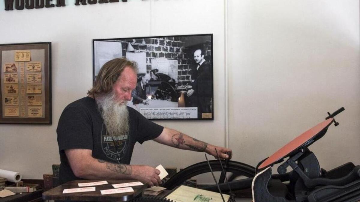 Loren Ackerman of the Tenino Depot Museum runs the 1890s-era printing press once used to print Tenino’s wooden money during the Depression. The press still prints wooden money that can be redeemed for goods at some area businesses.