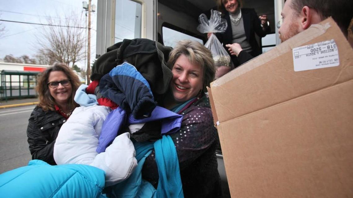 FILE PHOTO: Community Youth Services director Barbara Wakefield is loaded down with new coats as she collects donations from Heather Durka (left), Dawn Peterson and employees of Garden Courte Memory Care Center at the CYS offices in downtown Olympia in 2012. The agency is seeking gift cards for its clients for the holidays.