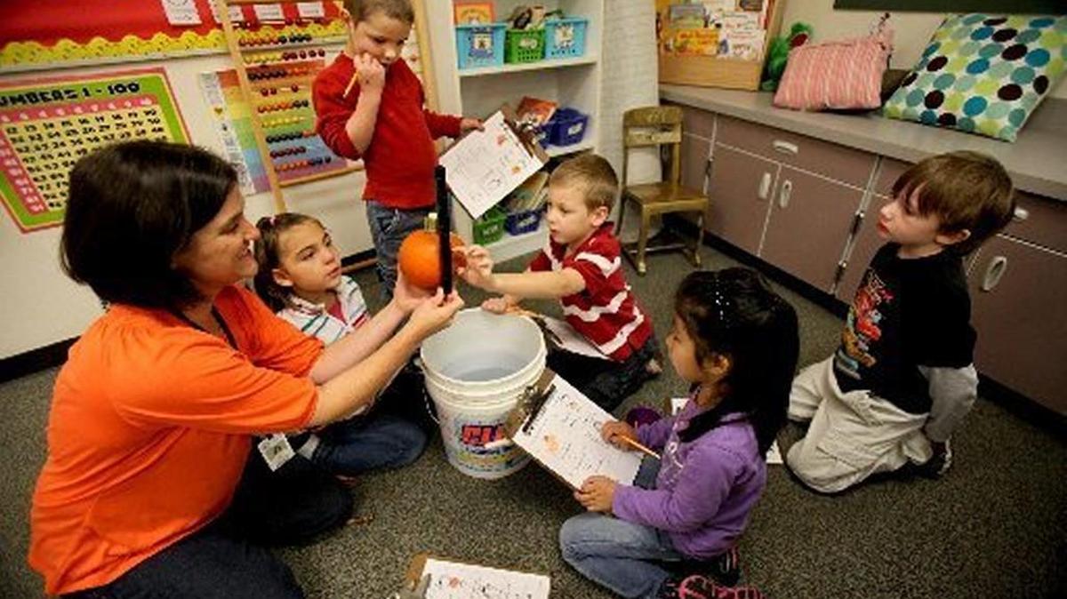 Olympian file photo: Lacey Elementary School general music specialist Cheri Kelley gets some assistance from kindergartner Dashiell Baker for a pumpkin measuring task as part of a multi-class project using the seasonal gourds for math learning in 2011. It’s the start of kindergarten registration season.