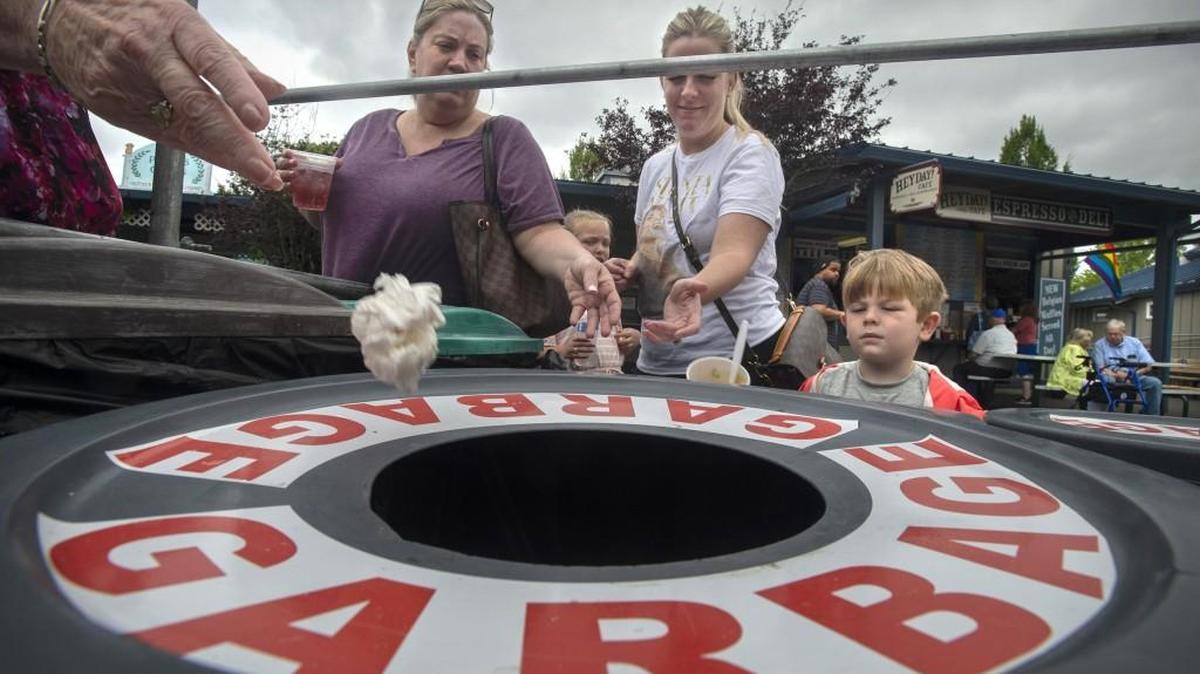 Families toss compostable waste into the garbage at the Olympia Farmers Market on June 22.