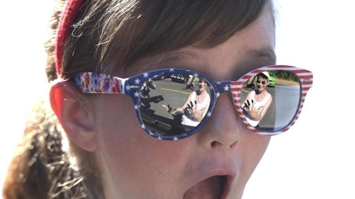 Alex Hames, 9, reacts with surprise as Shirley Jemelka shows off her decorated finger nails as they wait to roll with the Mustangs West car club in the annual Tumwater Fourth of July Parade down Capitol Boulevard on July 4, 2015.