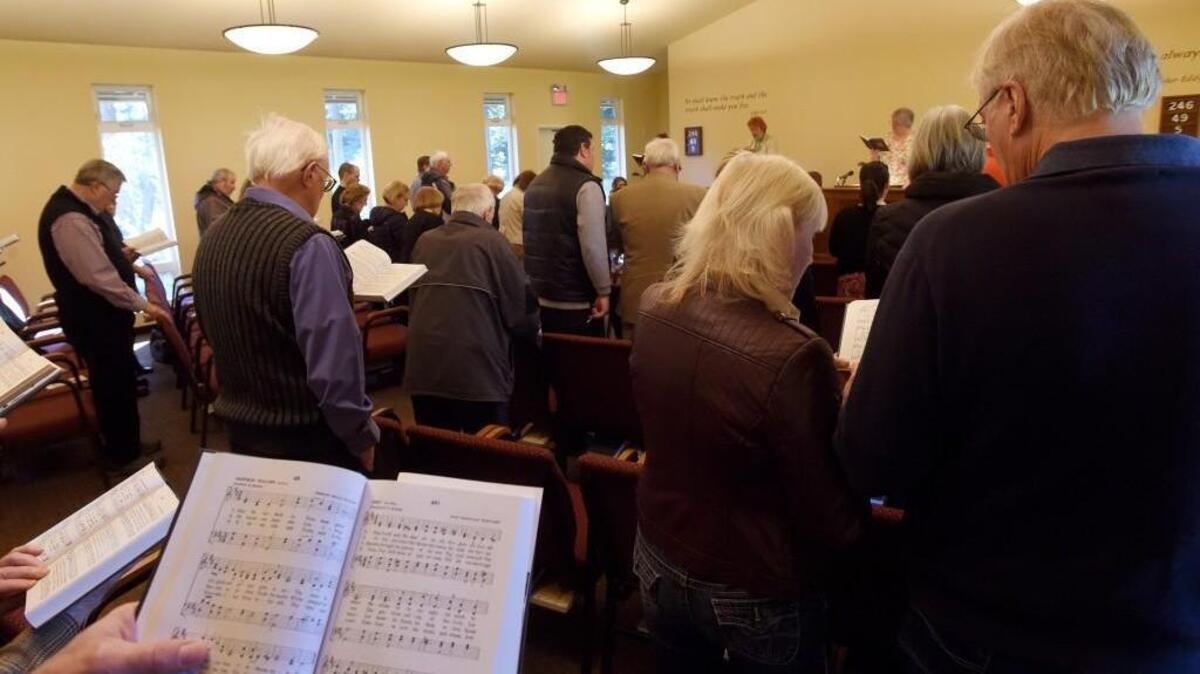 Church members and current readers Dottie Lehuta (left) and Suzanne Montgomery rise with their congregation to sing during the March 19th Sunday service at Olympia First Church of Christ, Scientist, as it celebrates 100 years.