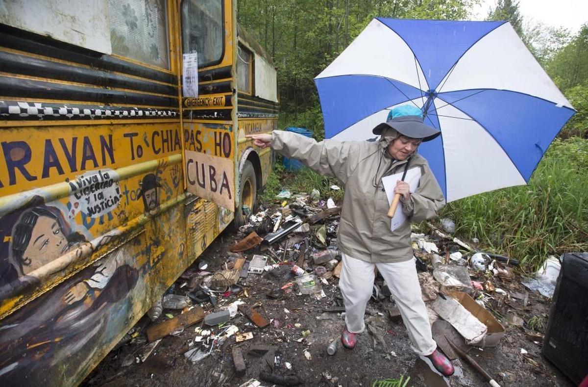 Angela Ducharme steps cautiously through the mess of trash on her 2.3-acre property in west Olympia.